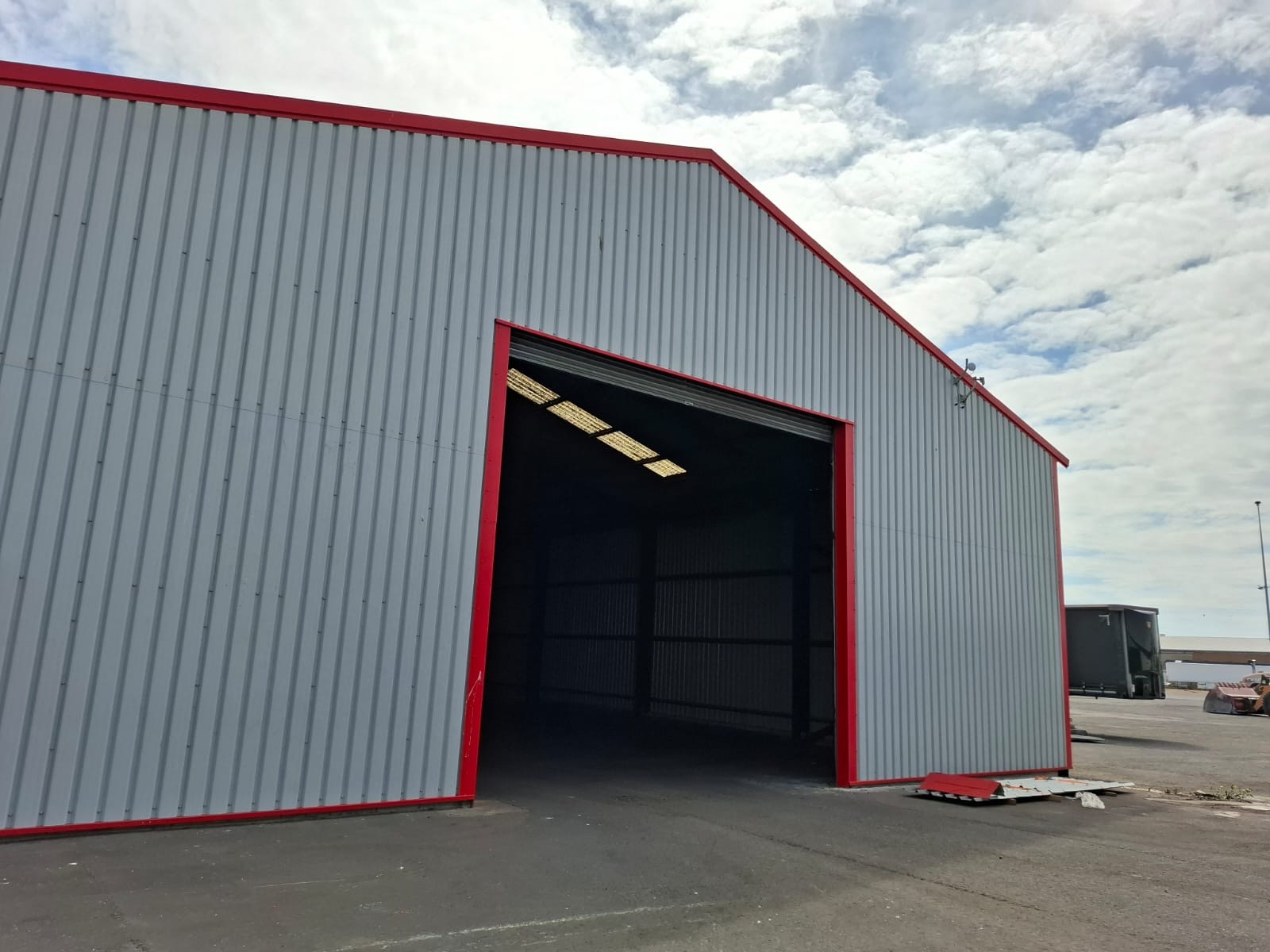 Grey profiled metal cladding on an industrial unit with red flashings - DB Roofing roofing and cladding project