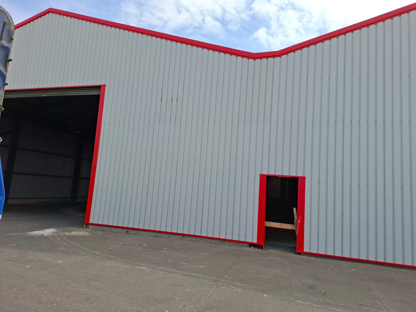 Industrial building clad in grey profiled metal sheeting with red trim - DB Roofing cladding project