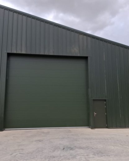 Dark green profiled metal clad industrial building with roller shutter door - DB Roofing project